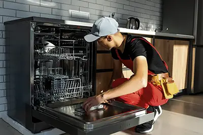 plumber kneeling by a dish washer